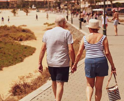 apparel man and woman walking on road while holding hands shorts