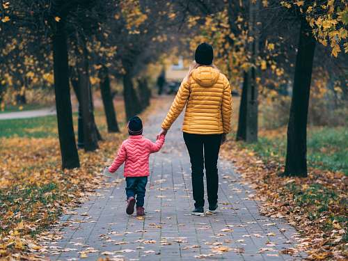 apparel person holding child walking on pathway footwear