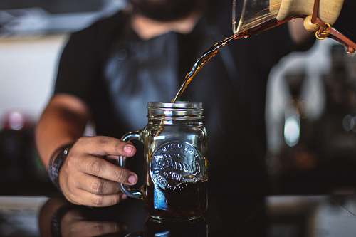 jar man pouring liquid on clear glass mason jar glass