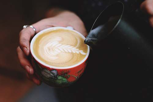 cup person doing coffee art on red ceramic mug beverage
