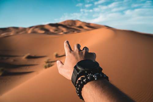 outdoors person pointing to dessert dune during daytime soil