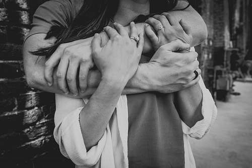 black-and-white grayscale photo of man hugging woman grey