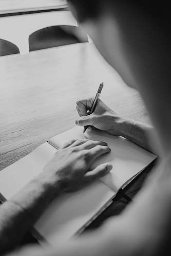 black-and-white grayscale photography of person writing on notebook grey