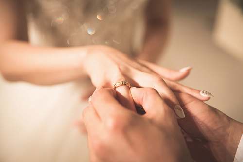 human man holding gold ring on woman's finger person