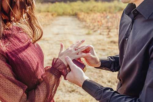 apparel man putting ring in woman's hand clothing