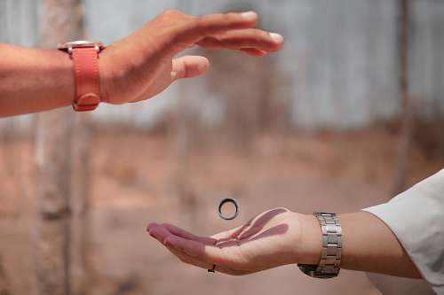 human mans hand above women with ring wristwatch