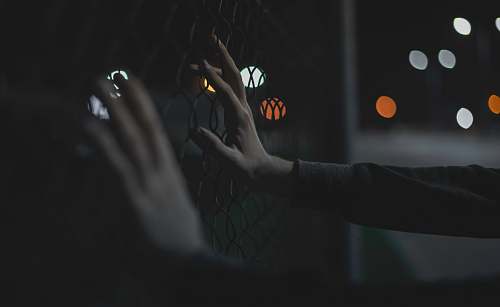 hands close-up photography of person grabing gray iron fence fingers