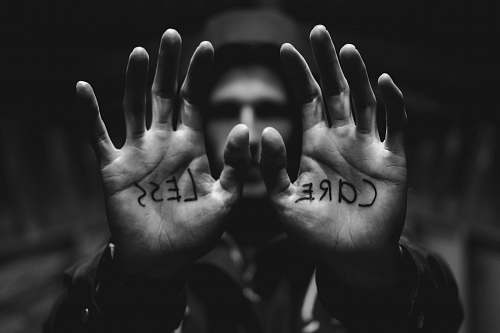 black-and-white gray scale photography of man raising both hands with care less text on palm grey
