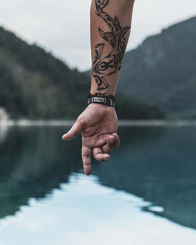 tattoo hand of person pointing to body of water with wrist tattoo holding hands