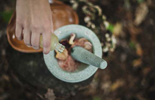 healing high angle photo of person pouring liquid from bottle inside mortar and pestle mortar
