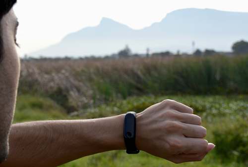 human man looking at black fitness tracker wrist