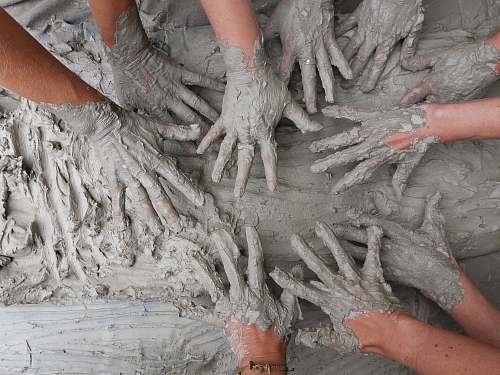 grey people's hand on gray mud clay