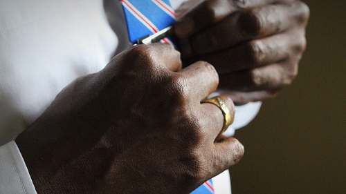 ring person holding blue necktie suit