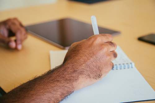 human person holding pen writing on book person