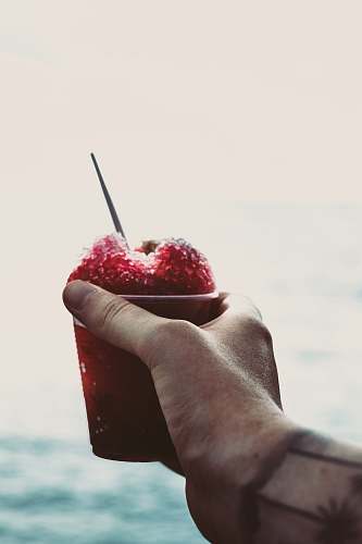 slushy person holding red dessert in cup fruit