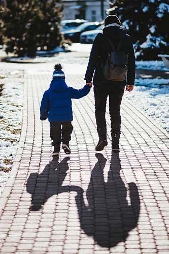 person person in black jacket holding hand with toddler holding hands