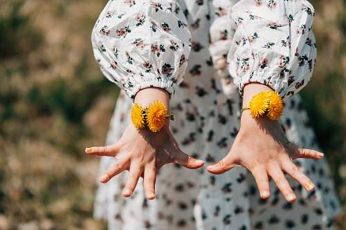 finger person showing orange petaled flower bracelet flower