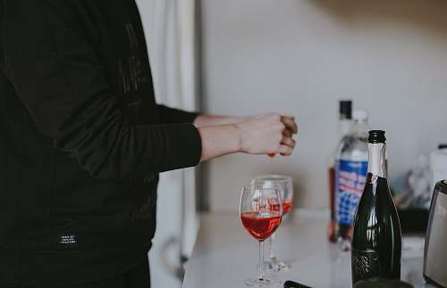wrist person standing beside two wine glasses bottle