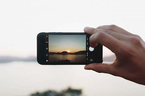 iphone person taking picture on mountain with sun mobile phone