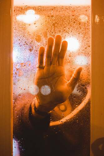 flare person's hand touching a clear glass pane light
