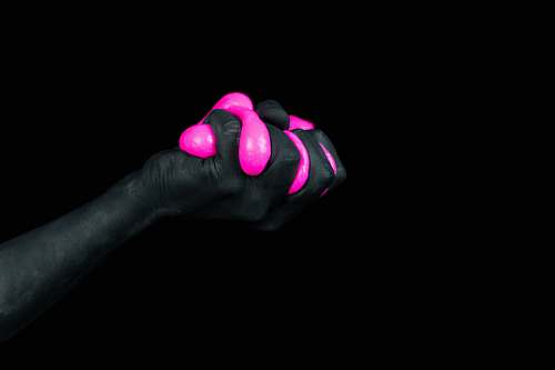 person selective color photography of hand holding pink balloon human