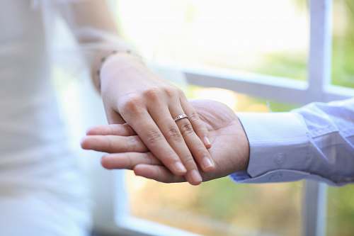 human selective focus photography of man holding women's right hand with ring holding hands