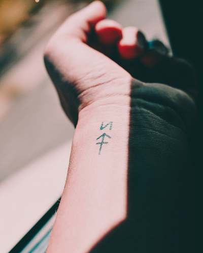 arm selective focus photography of person showing wrist tattoo skin