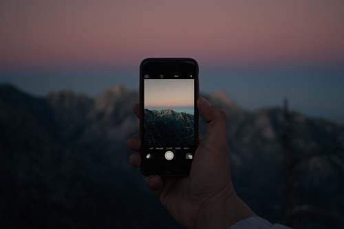 iphone selective focus photography of person taking photo using iPhone landscape