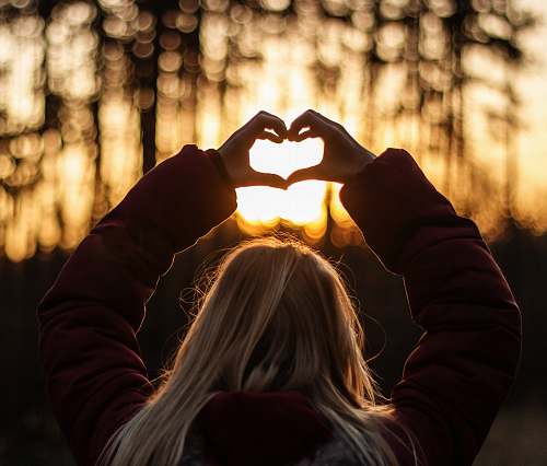 human selective focus photography of woman doing heart hand sign holding hands