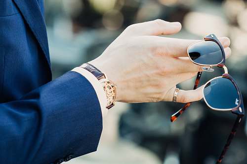 watch shallow focus photography of man holding sunglasses wrist