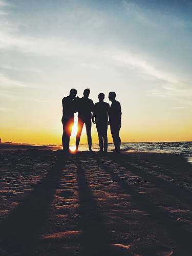 human silhouette photography of four person standing on shore person