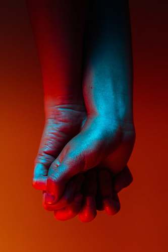 hands two person holding hands near orange background red