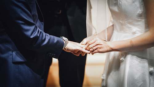person woman inserting ring on man's finger holding hands