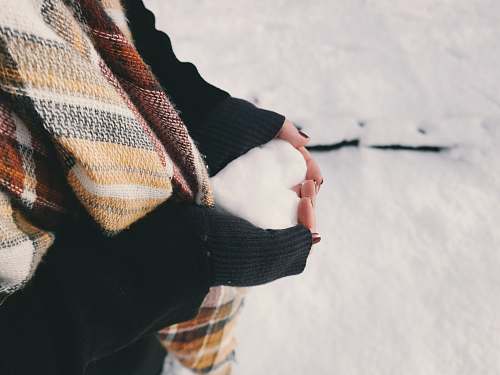 winter woman wearing black sweater holding ice forming heart snow