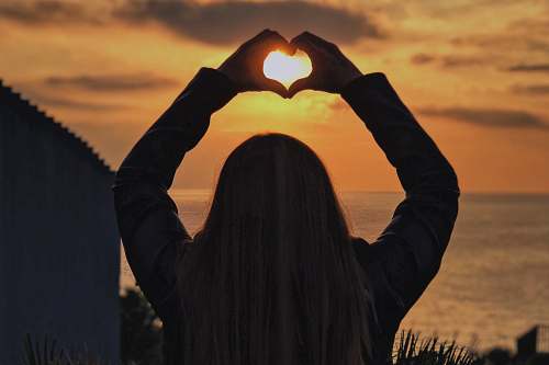 person woman with hands in heart shape at sunset human