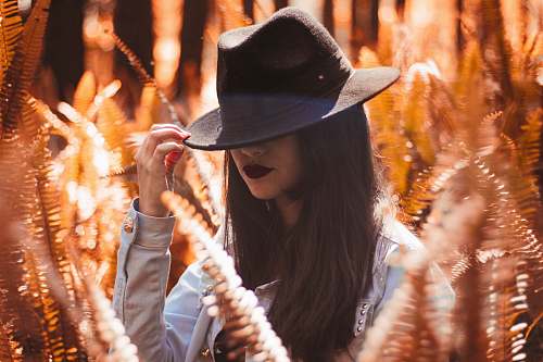 girl photography of woman in white long-sleeved top holding black bucket hat woman
