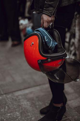 red person holding red half-face helme carrying helmet