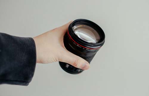 caucasian person holding black camera lens hold