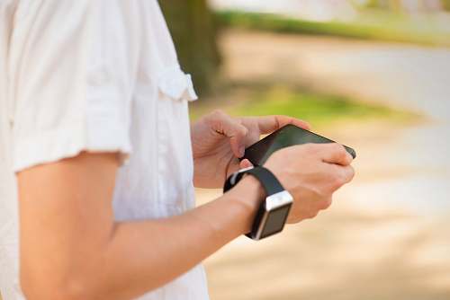hand closeup photo of person holding smartphone wristwatch
