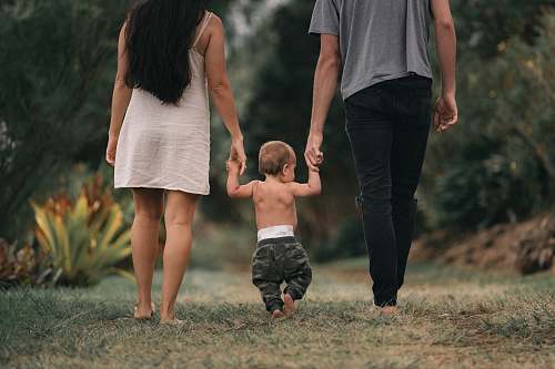 person couple walking barefoot with a child at the garden holding hands