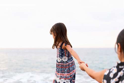 person girl holding girl overlooking body of water at daytime apparel
