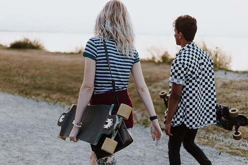 person man and woman in white-and-black tops walking on pathway during daytime apparel