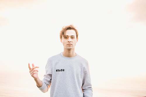 person man in gray sweatshirt raising his left hand people