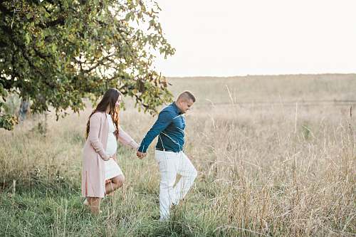 person man in green dress shirt holding woman's hand grass