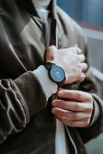 finger man standing while wearing round black analog watch wristwatch