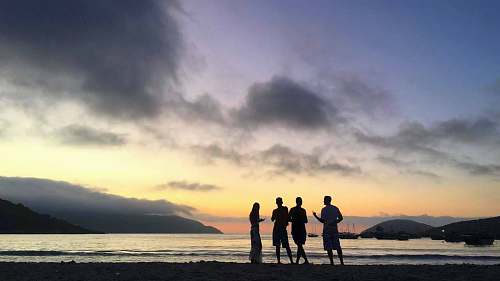 person people standing at the beach during golden hour standing