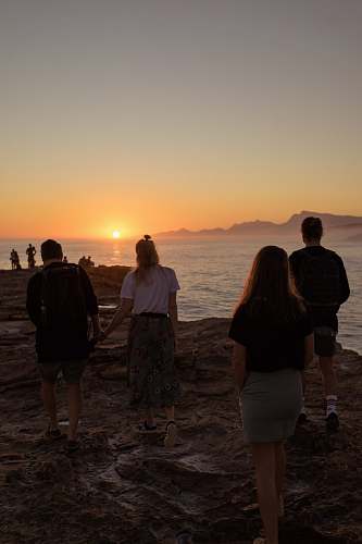 person people walking on rock near body of water during sunset people