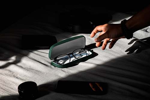 person person about to hold black-framed eyeglasses in case finger