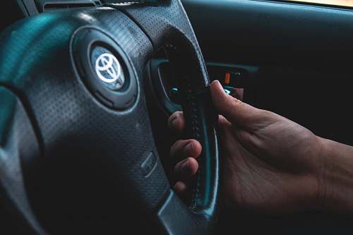 person person holding black Toyota vehicle steering wheel steering wheel