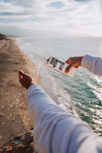 person person holding boxed water across seashore boxed water